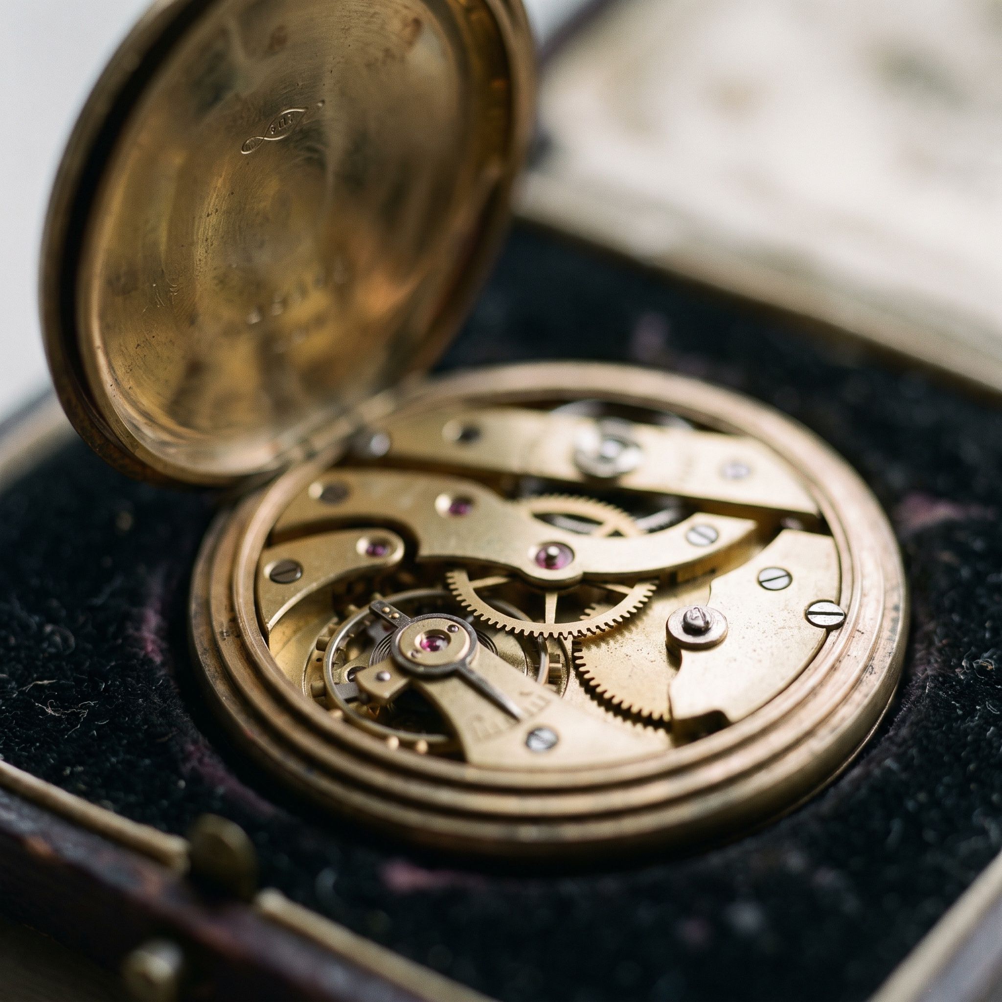 Macro photograph of an open antique pocket watch showing its brass gears and jewel bearings